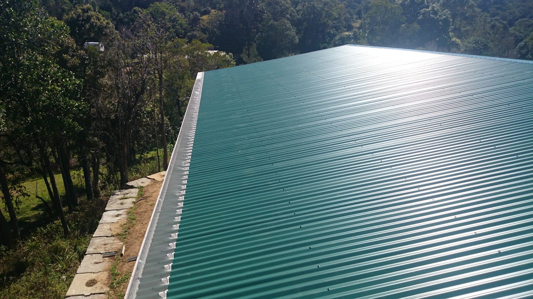 Gutter guard on a green Colorbond metal roof backed by gum trees